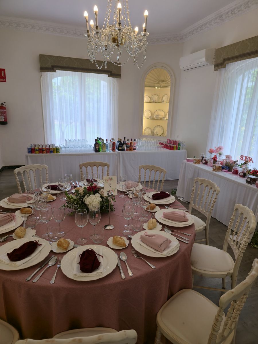 Salón de celebraciones con lámpara de araña y mesas montadas por el catering
