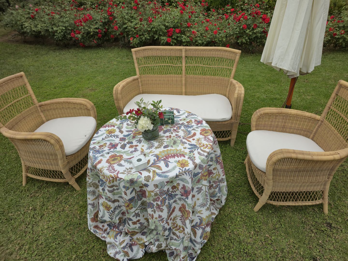Zona chill out con sillones de mimbre y mesa vestida en el jardín de una finca en Sevilla